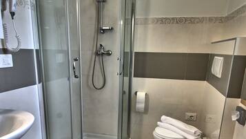 Ein Badezimmer mit einer Duschkabine, einem Waschbecken, einem Bidet und einer Toilette.