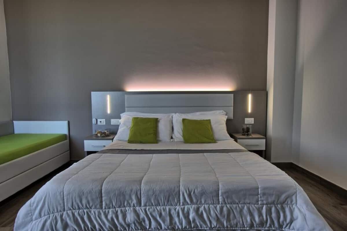 Ein modernes Hotelzimmer mit einem großen Bett, zwei Nachttischen und einem Beistelltisch.