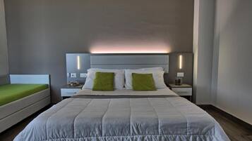 A modern hotel room with a large bed, two bedside tables, and a nightstand.