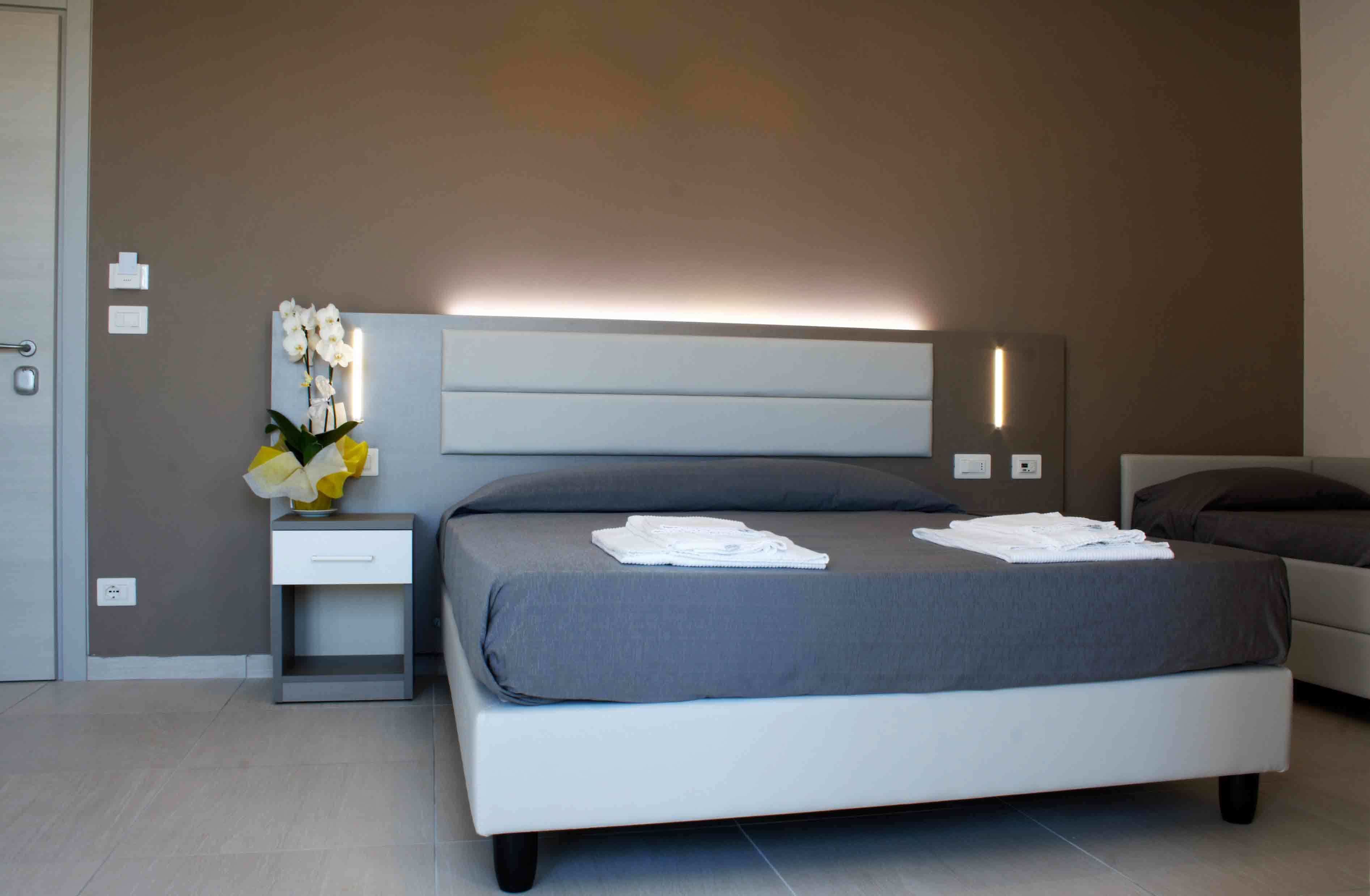 A modern bedroom with a bed, bedside table, and a wall-mounted light fixture.