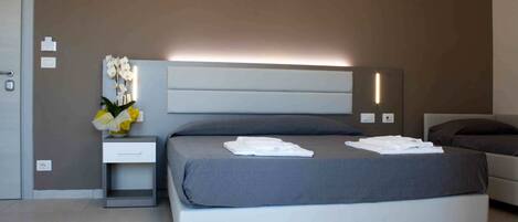 A modern bedroom with a bed, bedside table, and a wall-mounted light fixture.