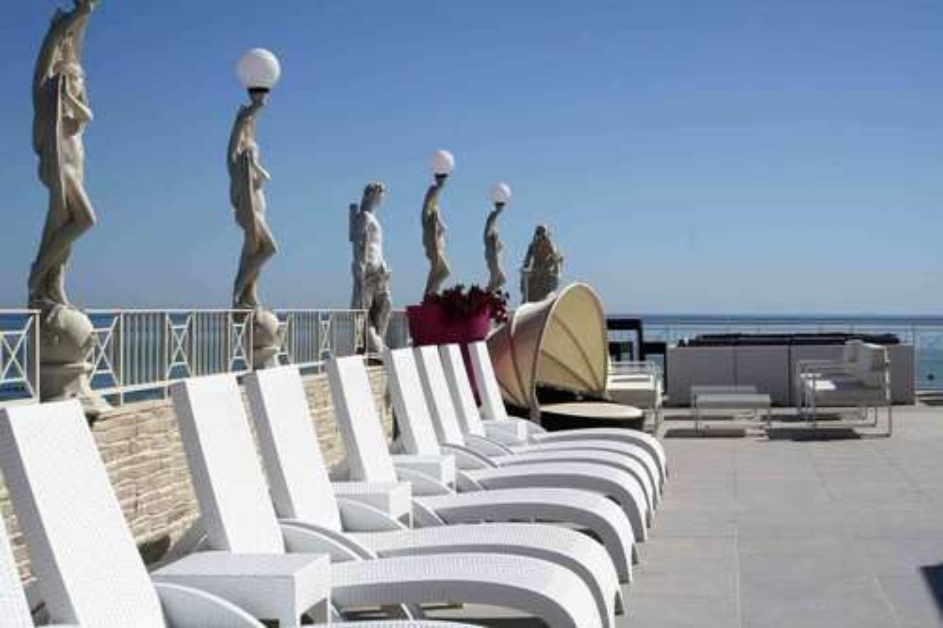 Terraza en la azotea con sillones blancos y vistas al mar.