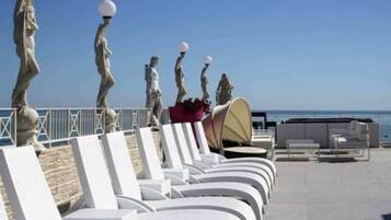 Terraza en la azotea con sillones blancos y vistas al mar.