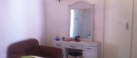 A bedroom with a bed, a dresser, a mirror, a television, and a wardrobe.