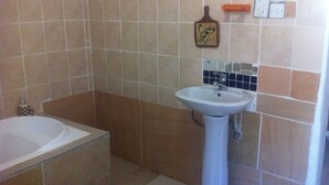Une salle de bain avec une baignoire, un lavabo et des murs carrelés.