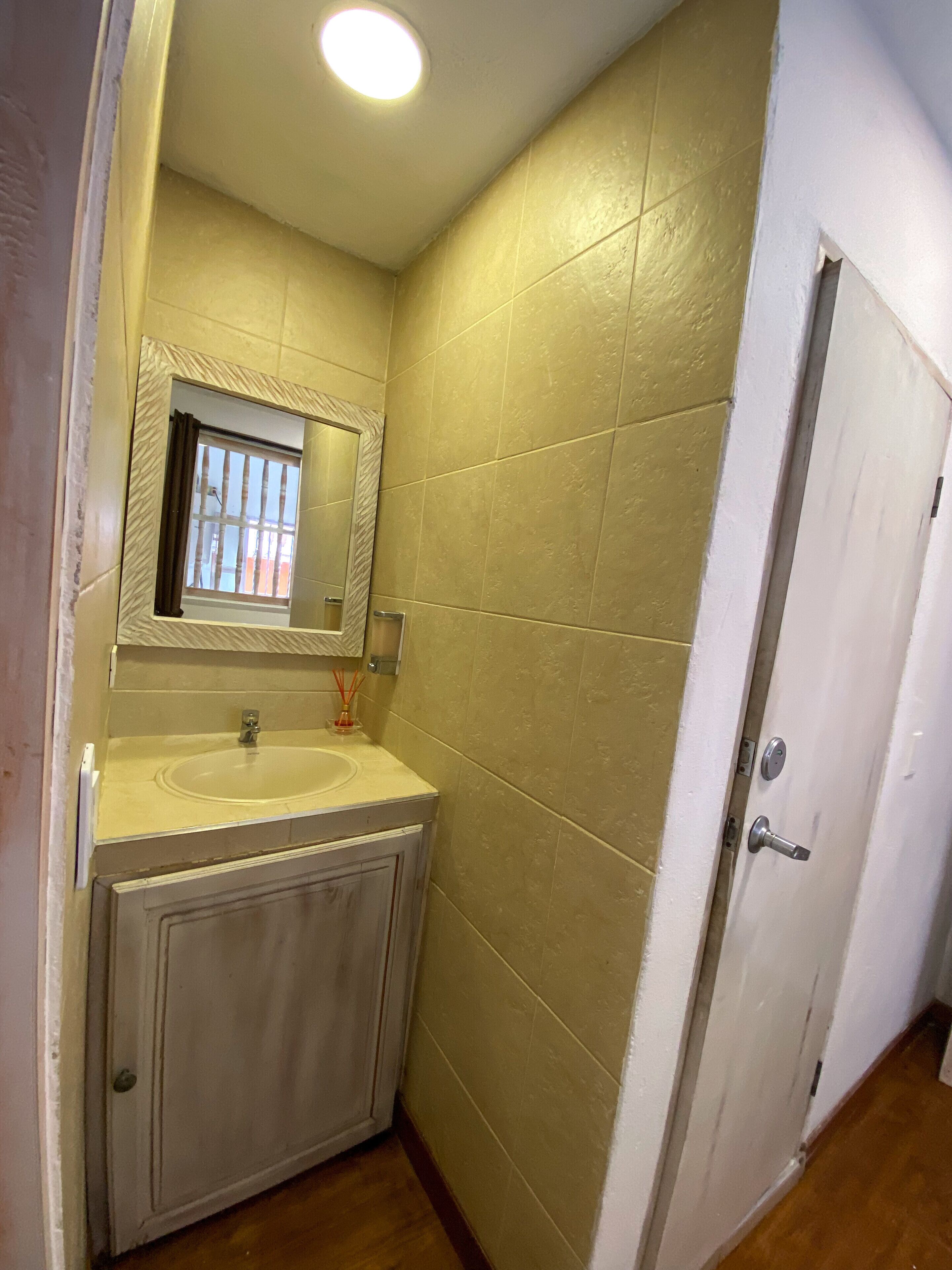 Une petite salle de bain avec un lavabo, un miroir et une porte.