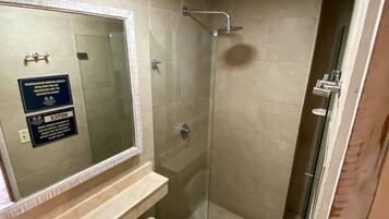 Un baño con inodoro, lavamanos y cabina de ducha de vidrio.