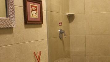 A bathroom with a sink, two toilets, a shower, and a framed picture on the wall.