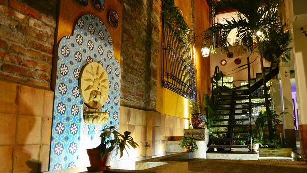 A staircase with a metal railing, a patterned wall, and potted plants. - Magic Garden House (Cali)