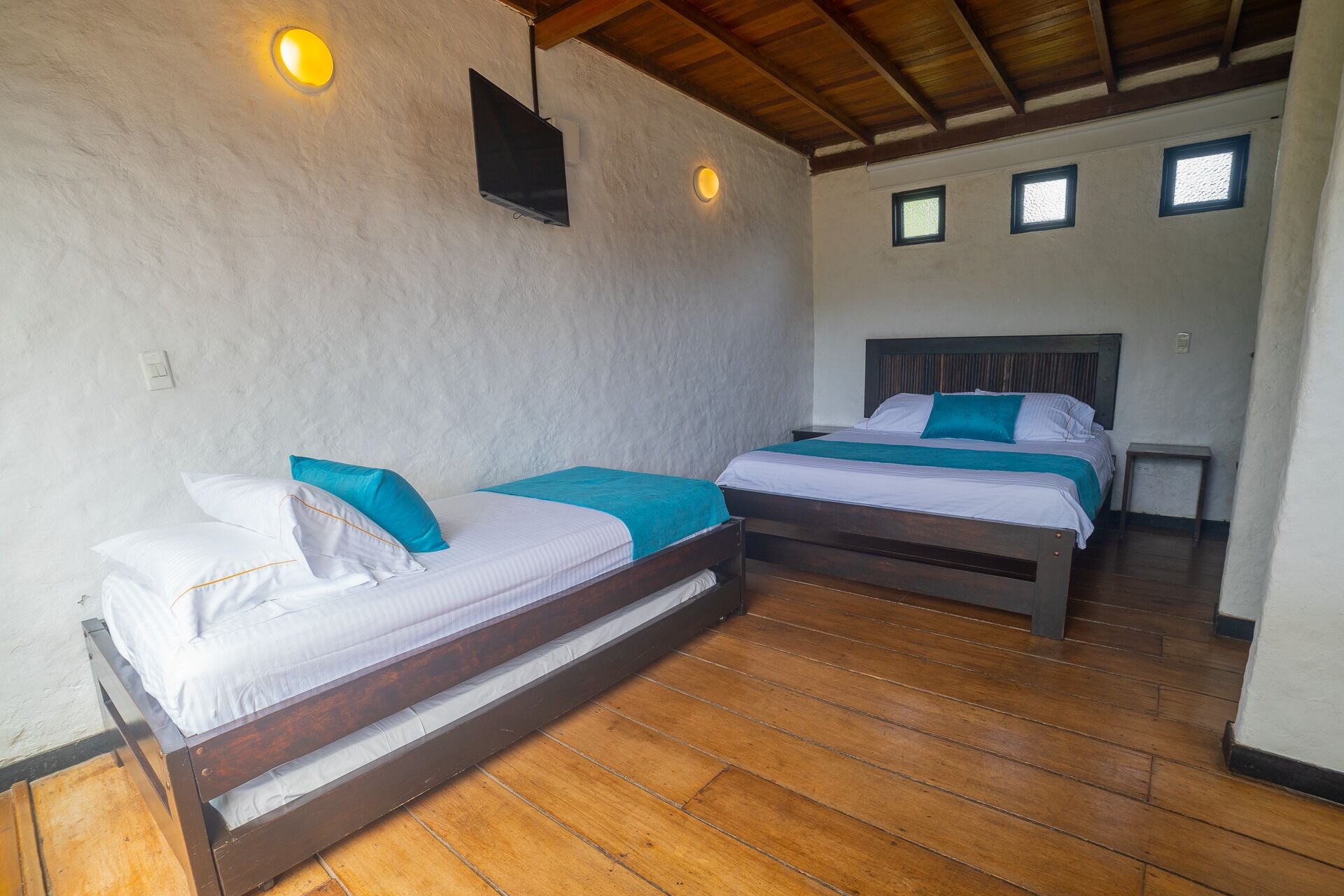 Una habitación con dos camas individuales, suelo de madera y techo inclinado.