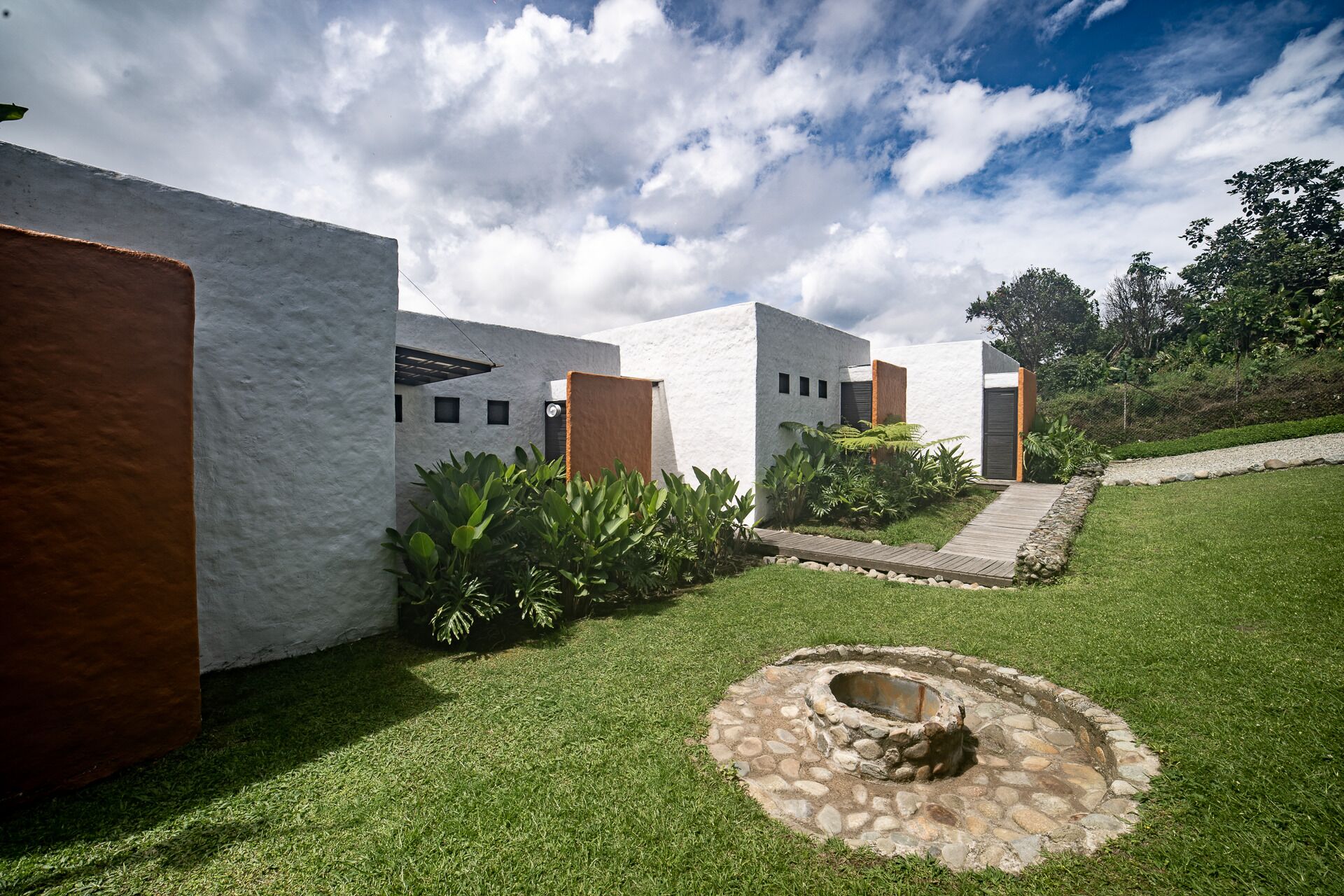 A modern building with white walls and a stone fire pit in the center.