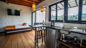 A compact kitchen with a wooden bench, a dining table, and a large window with a view. - Salento Pequeño Hotel (Salento)