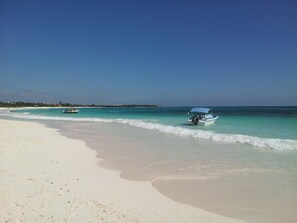 In Strandnähe, weißer Sandstrand, Sonnenschirme, Strandtücher