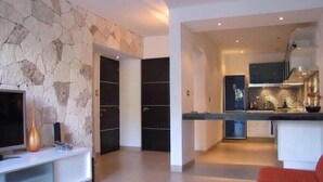 A modern kitchen with a stone wall, built-in cabinets, and a large island. - Casa Venecia (Playa del Carmen)