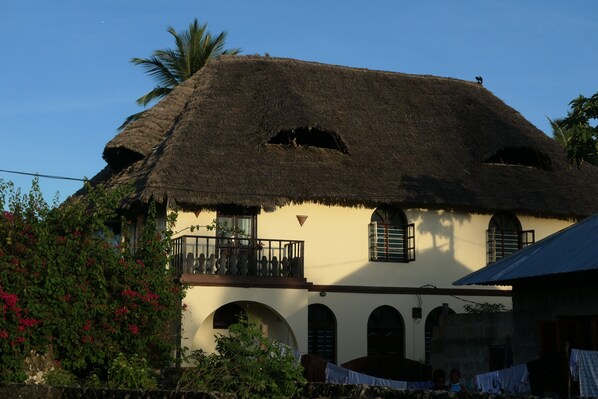 A traditional house with a thatched roof, arched windows, and a balcony.