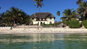 A beachfront property with a large house, palm trees, and a clear blue sky. - Seafront private villa at Jambiani Beach, Zanzibar (Jambiani)