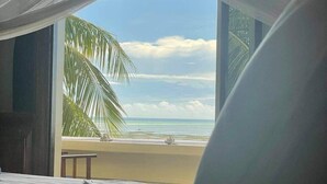 A room with a bed, a window overlooking a beach, and a palm tree. - Seafront private villa at Jambiani Beach, Zanzibar (Jambiani)
