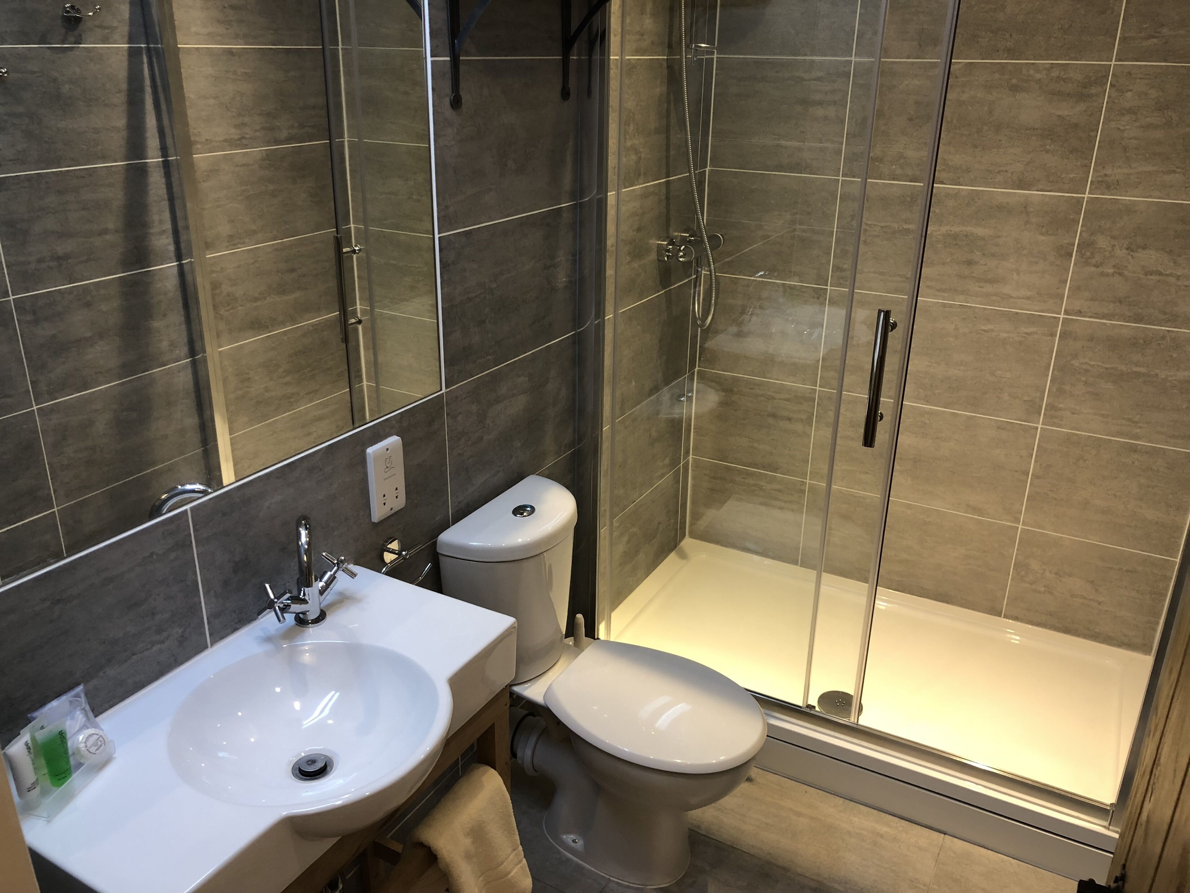 A modern bathroom with a glass-enclosed shower, a white sink, and a toilet.