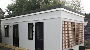Un bâtiment moderne doté de trois portes à encadrement noir, numérotées 1, 2 et 3, et d’une structure en treillis de bois sur le côté droit.