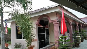 A building with a tiled roof, a large glass entrance, and multiple potted plants around the entrance. - Kampung Guest House - Hostel (Langkawi)