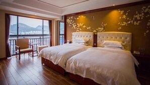 Habitación de hotel con dos camas, un balcón con una silla y vistas a montañas.
