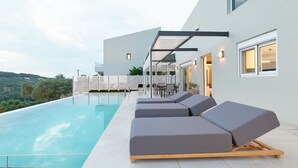 A modern outdoor pool area with lounge chairs and a glass-enclosed patio. - Suitable For Families With Children, Groups Of Friends, Professionals, Friends (Rethimno)