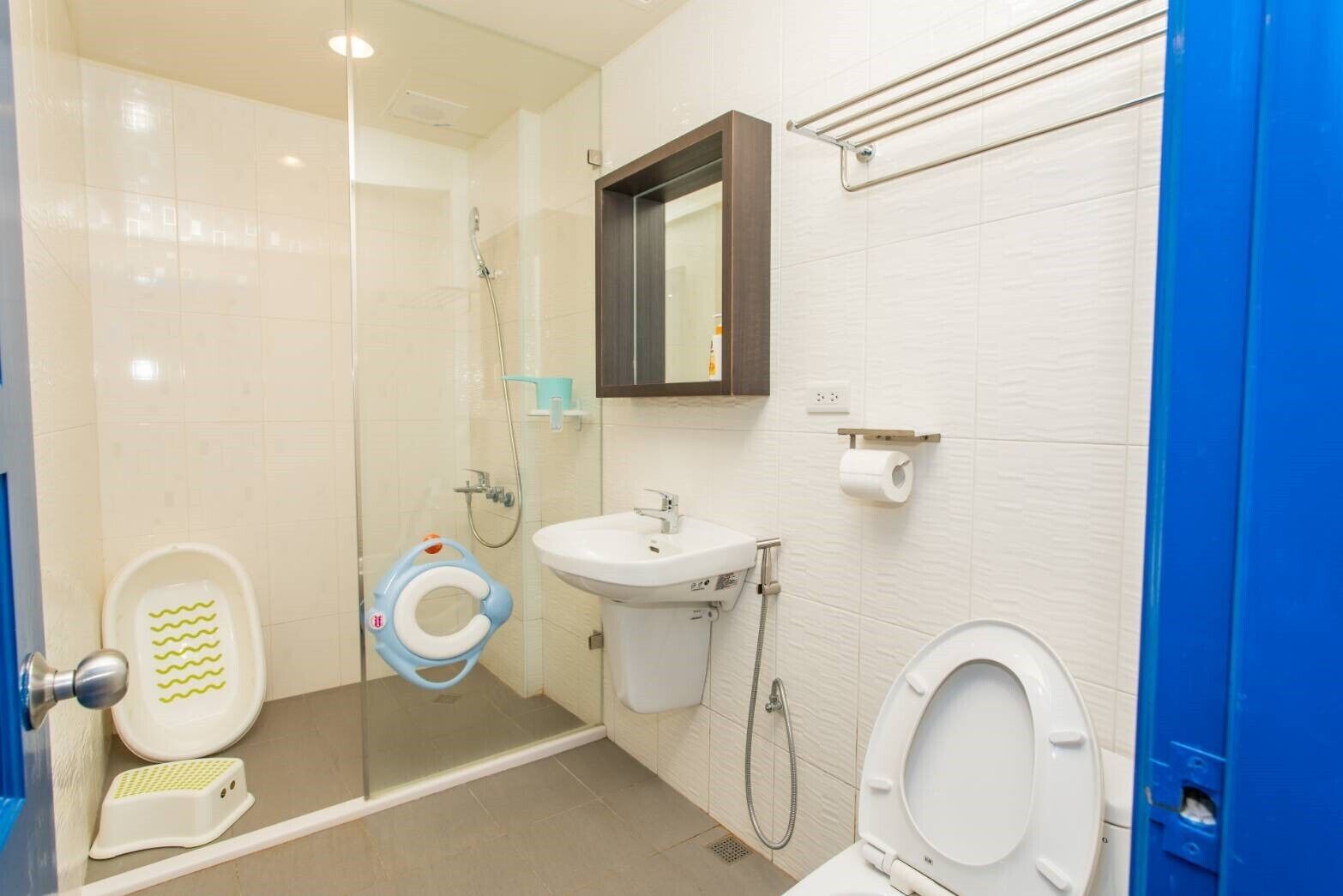 Un baño con mampara de vidrio, lavamanos, inodoro y bidé.