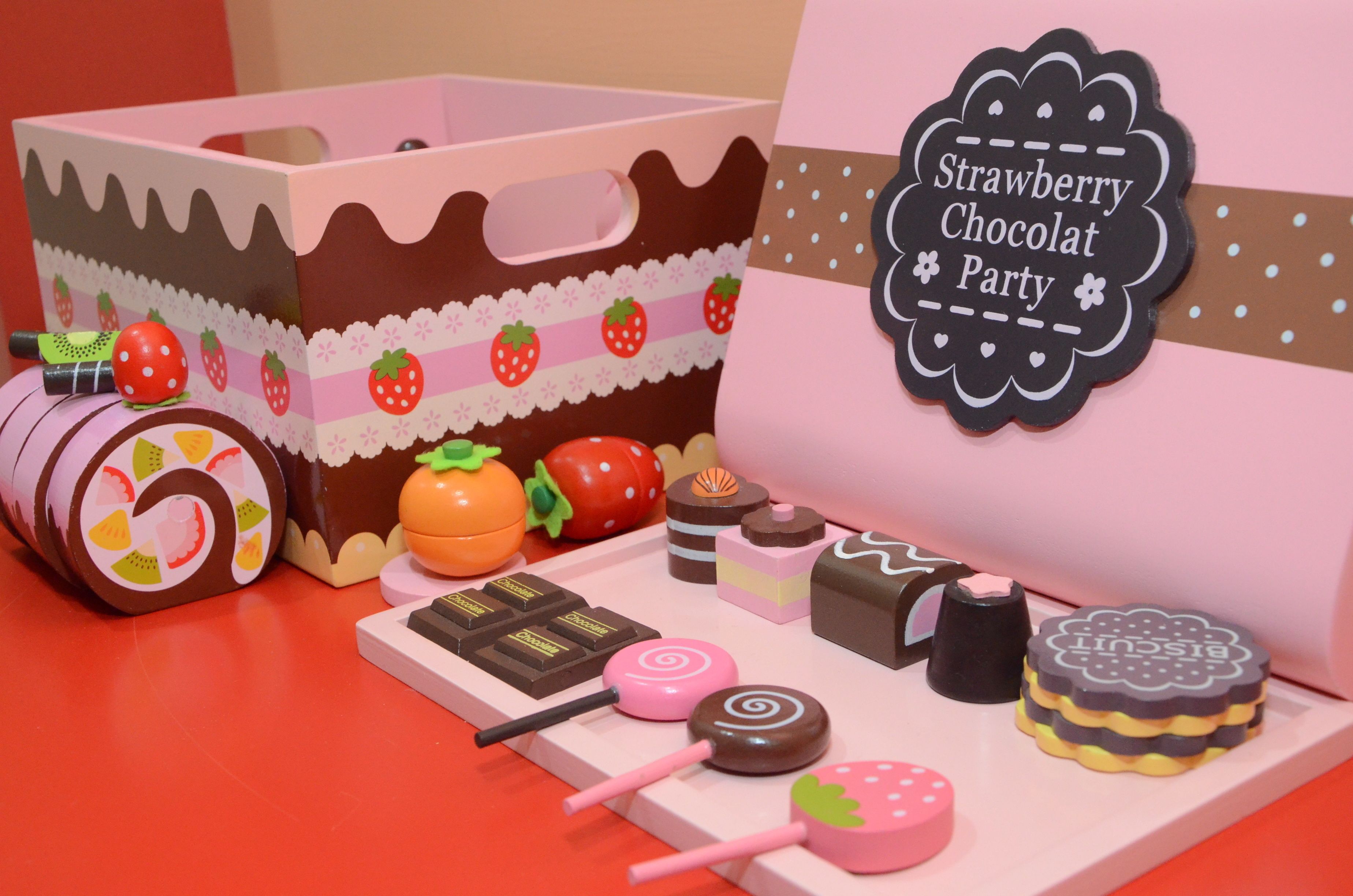 A display of miniature confectionery items including a cake box, lollipops, and a sign indicating a 'Strawberry Chocolat Party'.