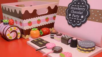 A display of miniature confectionery items including a cake box, lollipops, and a sign indicating a 'Strawberry Chocolat Party'.
