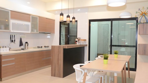 A modern kitchen with wooden cabinets, a central island, and pendant lighting. - Fat Snail BnB (Tainan)
