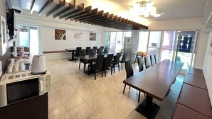 A modern dining area with a long table and chairs, a microwave, and a refrigerator. - Cest la vie B&B (Hengchun)