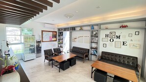 A modern living room with a wooden coffee table, leather sofas, and a built-in bookshelf. - Cest la vie B&B (Hengchun)