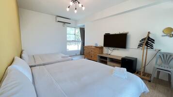 A hotel room with two beds, a TV, a wooden cabinet, and a desk.