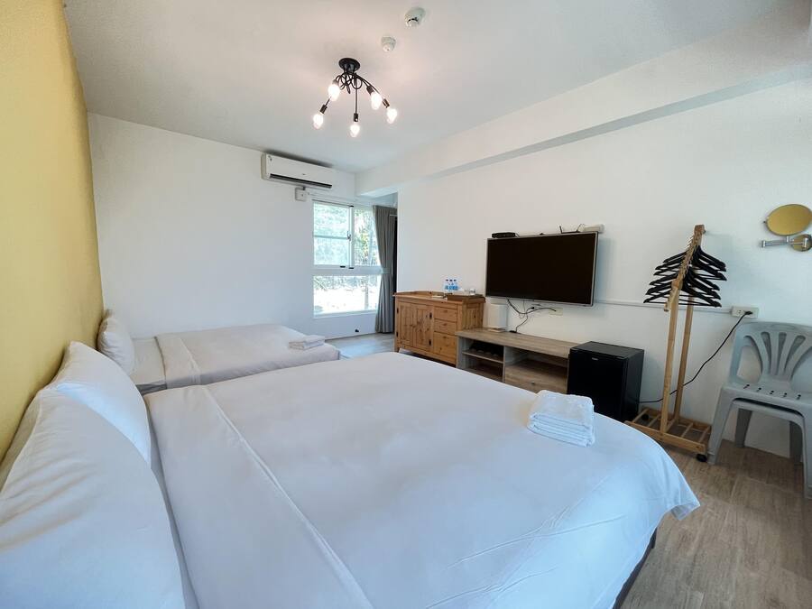 A hotel room with two beds, a TV, a wooden cabinet, and a desk.