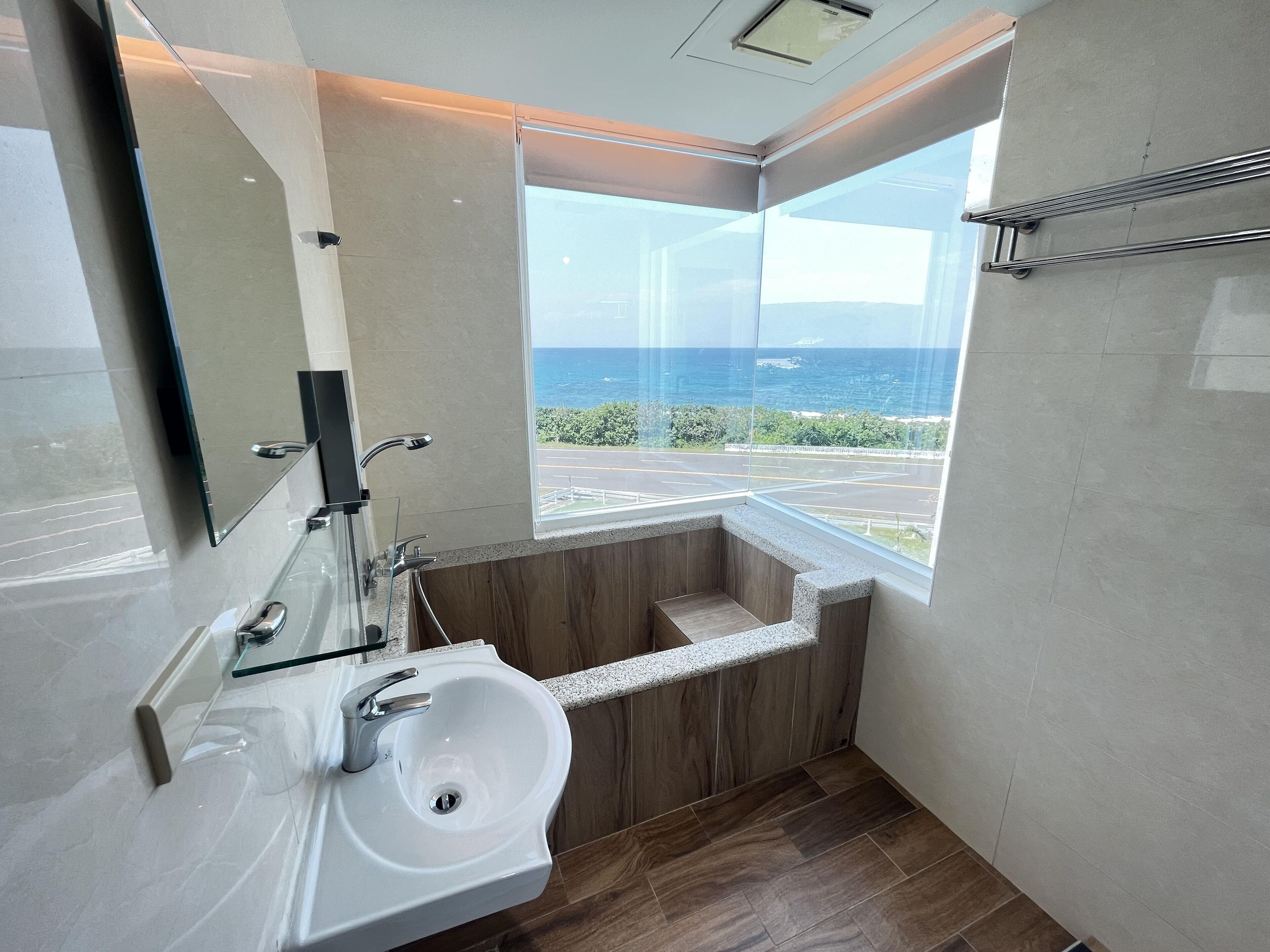 A modern bathroom with a large window, a built-in sink, and a wooden vanity.