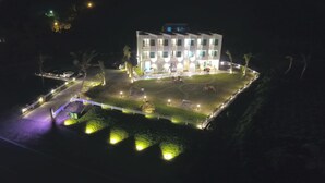A multi-story building with a well-lit courtyard, surrounded by a fence and featuring a swimming pool and outdoor seating areas. - Cest la vie B&B (Hengchun)
