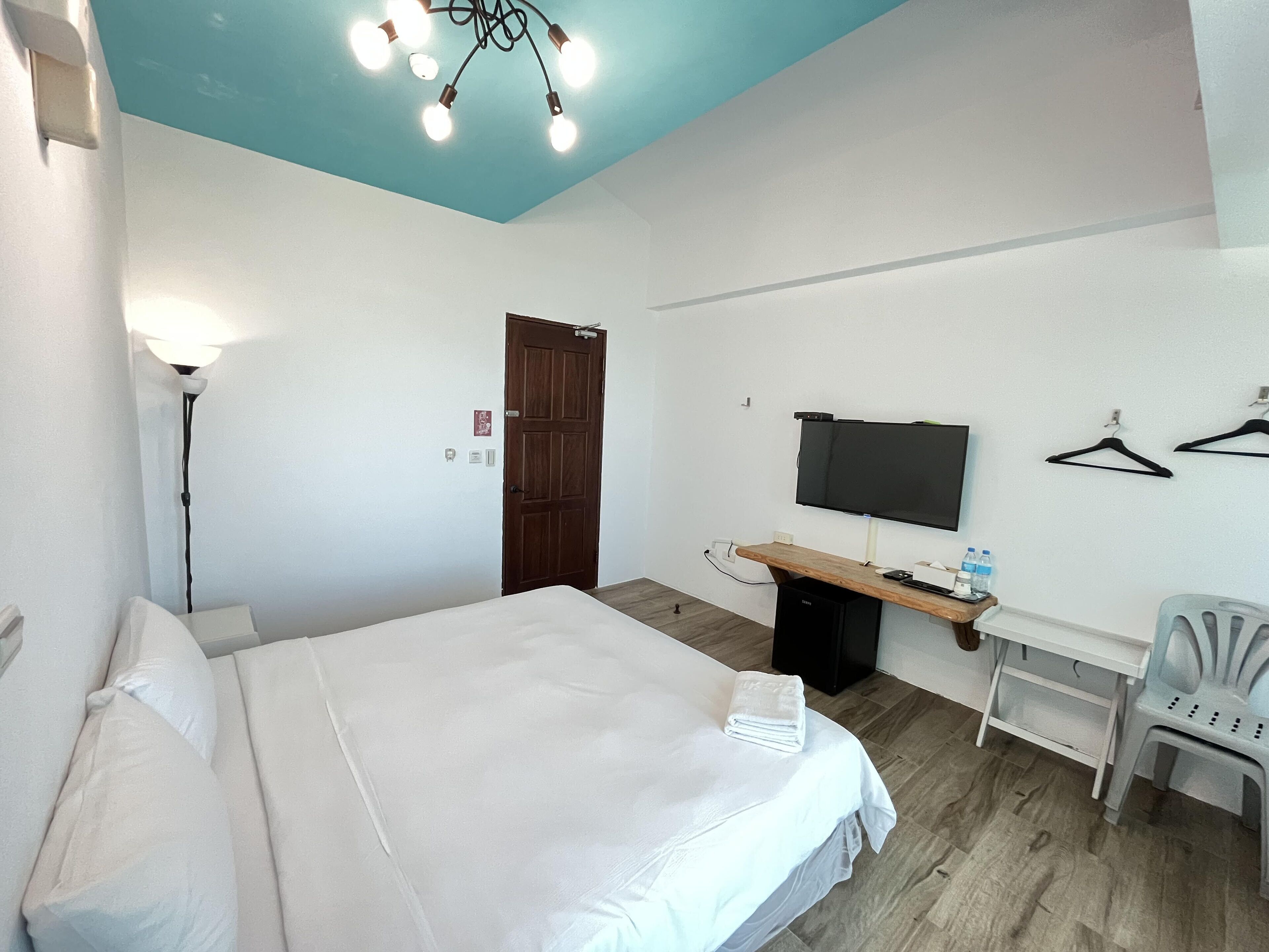 Een hotelkamer met een bed, een bureau met een televisie, een stoel en een kledingkast.