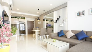 A modern living room with a sofa, coffee table, and chairs. There is a kitchen in the background with a dining area. - Ami Splendid Rooftop Pool (Ho Chi Minh City)