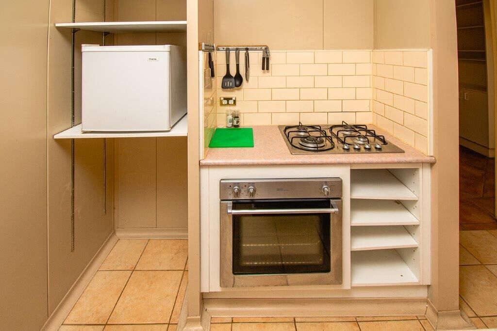 A compact kitchen with a built-in oven, a gas stove, and a small refrigerator.
