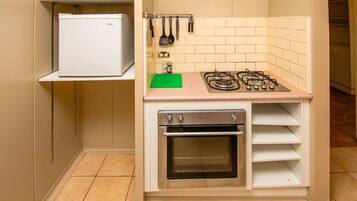 A compact kitchen with a built-in oven, a gas stove, and a small refrigerator.