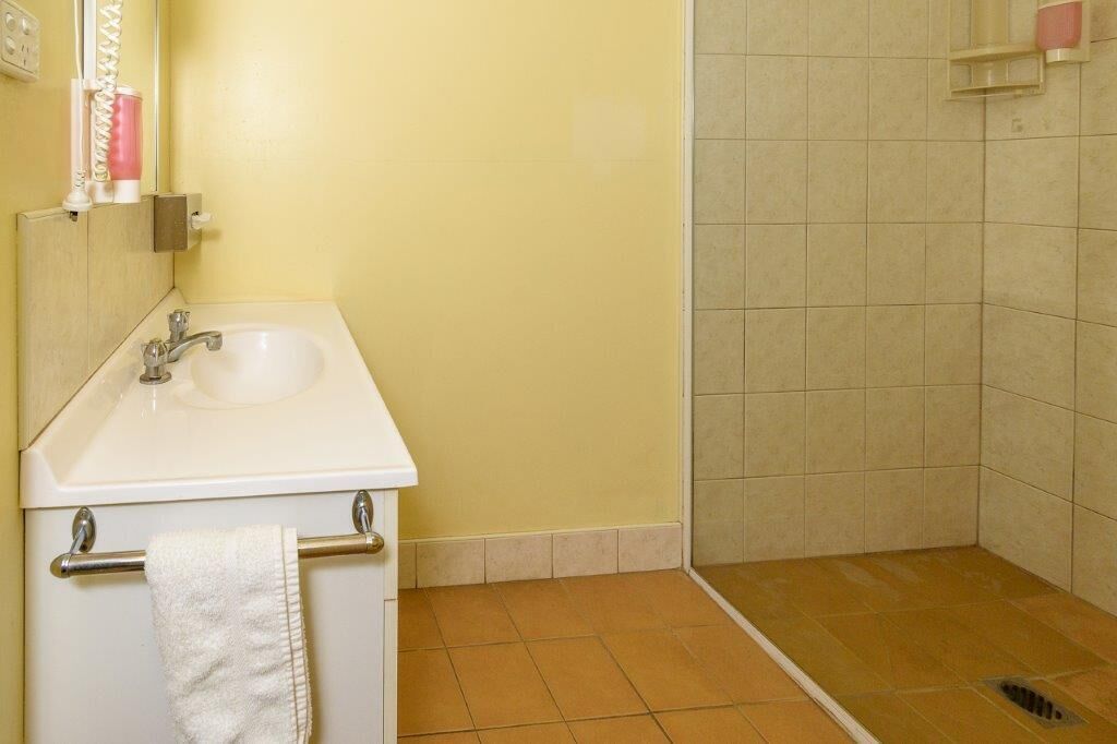 Une salle de bain équipée d’un lavabo, d’un miroir, d’un porte-serviettes et d’une zone douche.