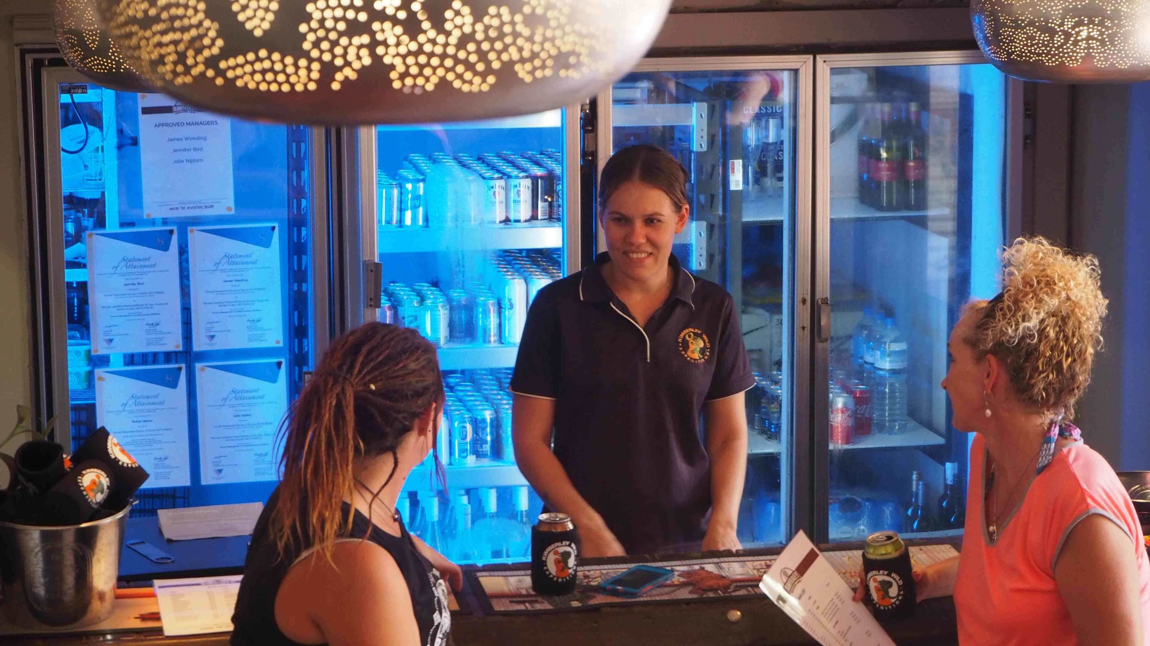 A bar area with a counter, a refrigerator stocked with beverages, and a menu on the counter.