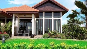 Uma casa moderna com telhado inclinado, janelas grandes e um jardim bem cuidado.