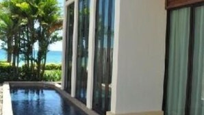 Um edifício moderno com piscina, janelas amplas e vista para o oceano.