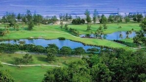 Um campo de golfe com vários lagos e vista para o oceano.