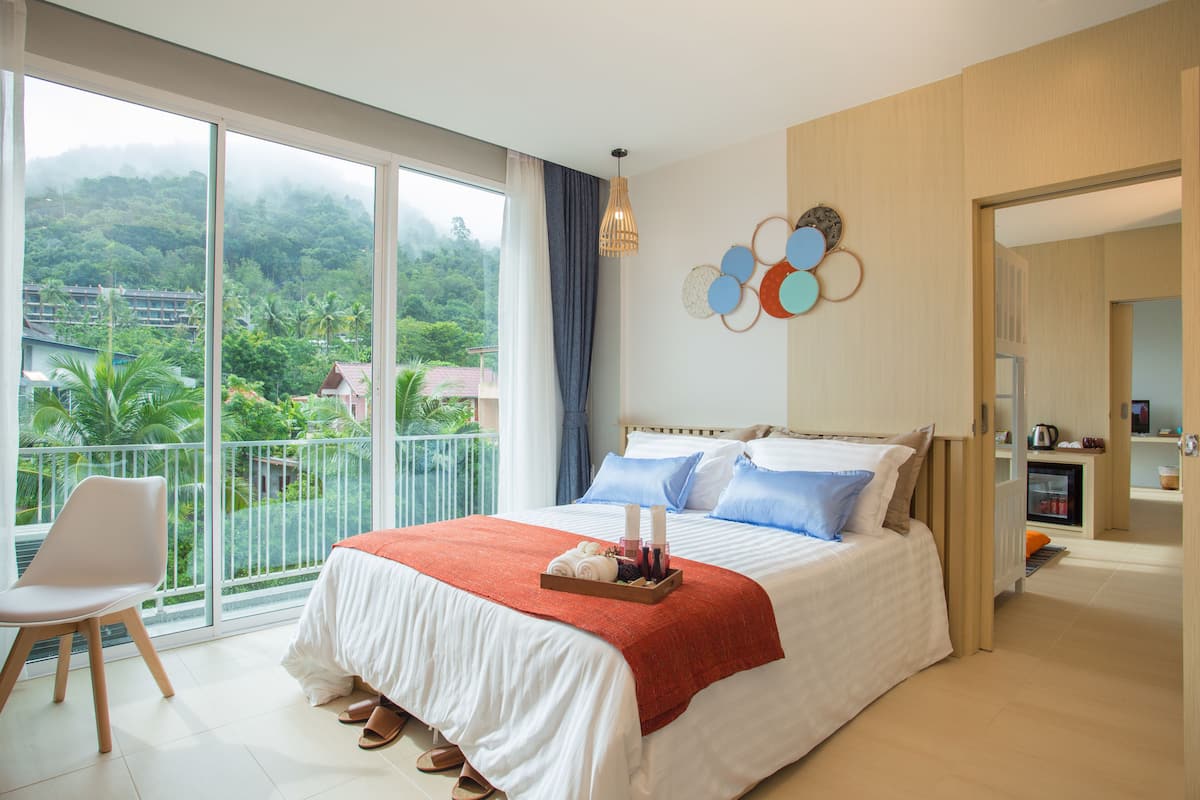 Un dormitorio con una cama grande, vistas a zonas verdes, un balcón y una decoración de estilo moderno.