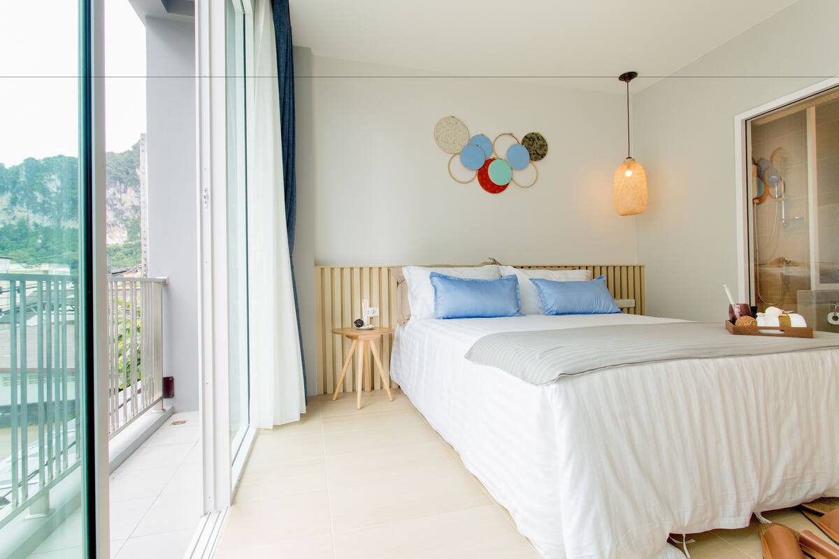 Un dormitorio moderno con una cama grande, una mesita de noche pequeña y vistas a un balcón.