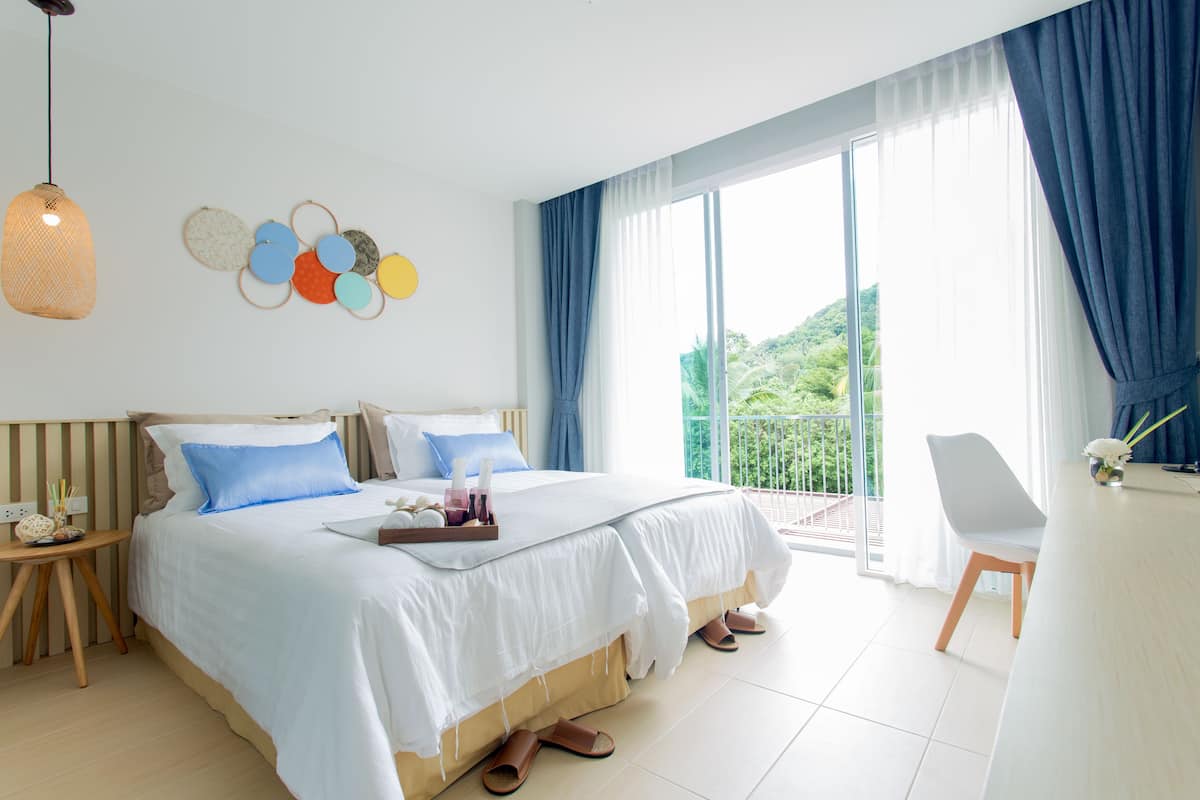 Una habitación de hotel moderna con una cama grande, un escritorio y un balcón con cortinas azules.