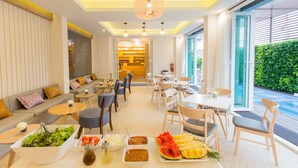 A modern hotel lobby with a dining area, seating arrangements, and a view of the outdoors.