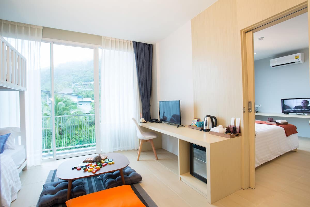 Una habitación de hotel moderna con balcón, un escritorio con computadora, cama y sofá.